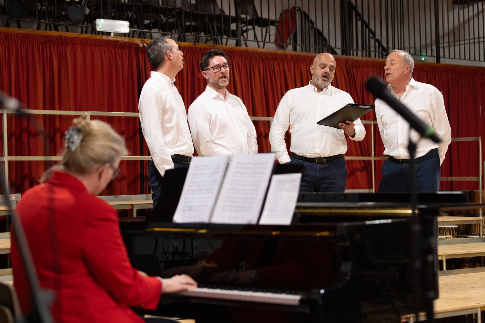 A small group of singers performing around a grand piano